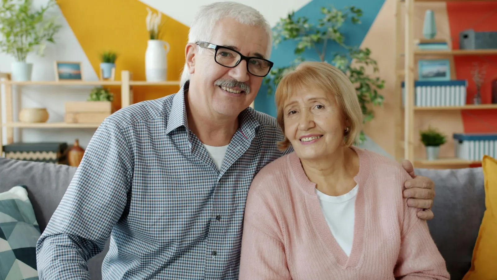 A smiling older couple sitting close together on a sofa at home